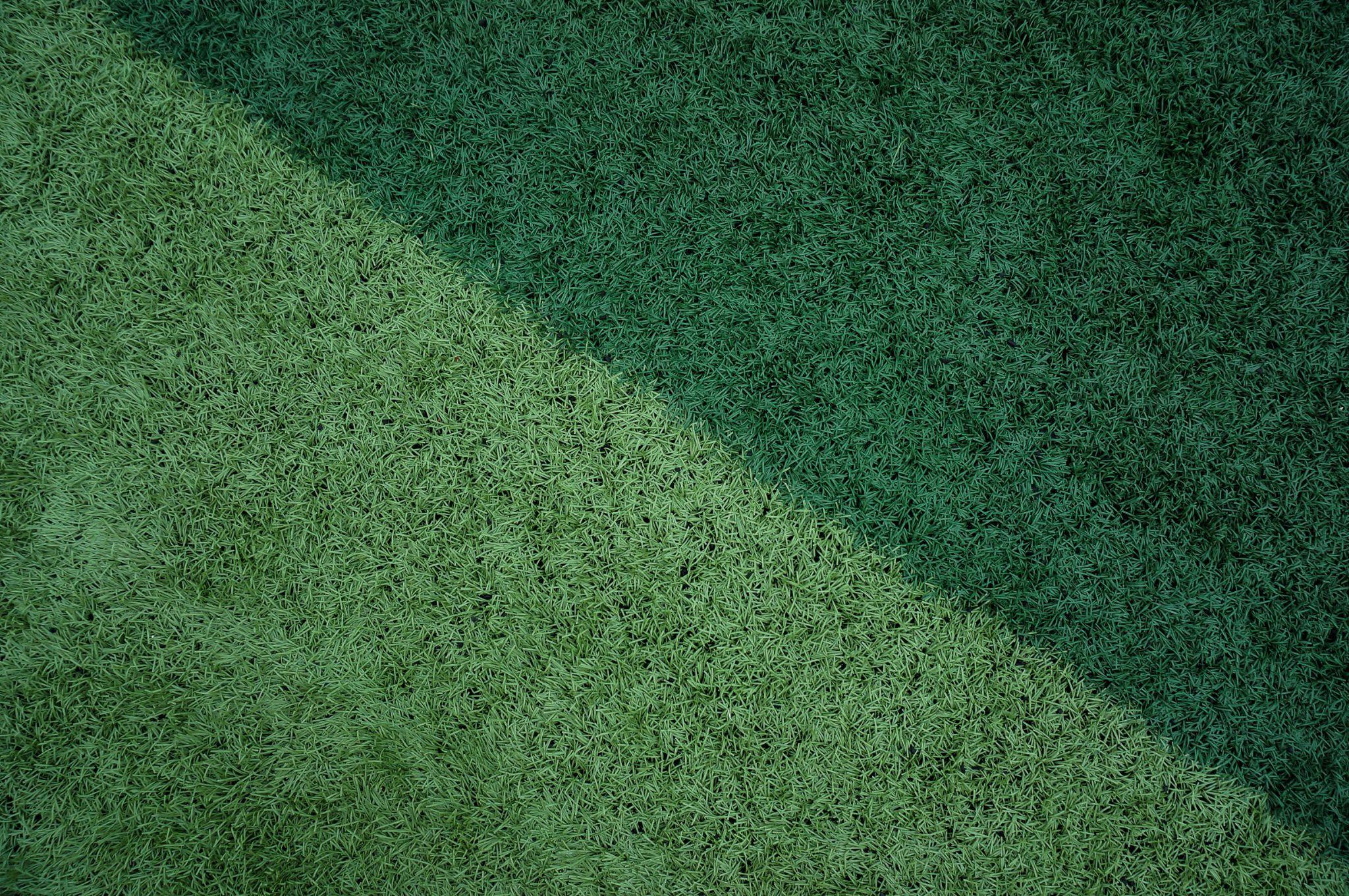 Two shades of artificial turf forming a diagonal pattern in natural light