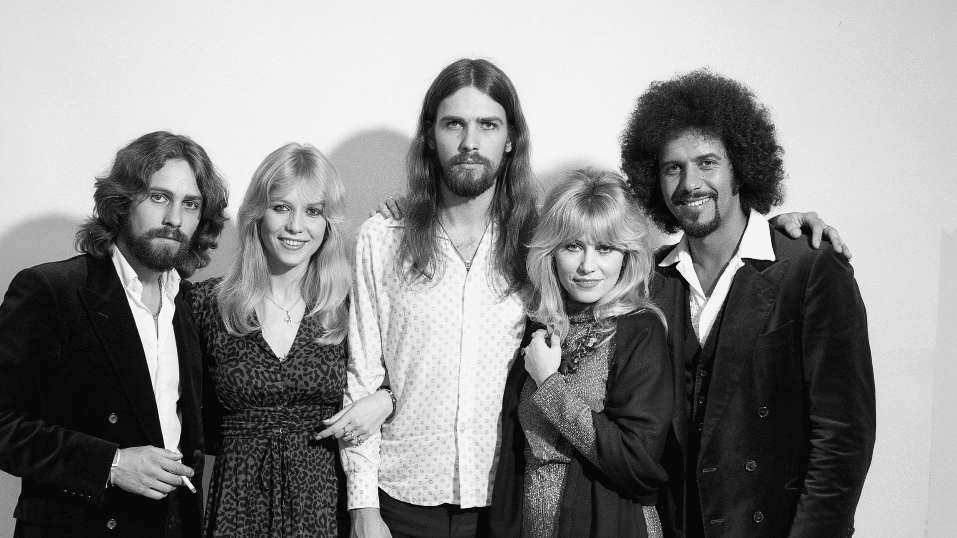 A black-and-white group photograph of the band Fleetwood Mac posing together outdoors.