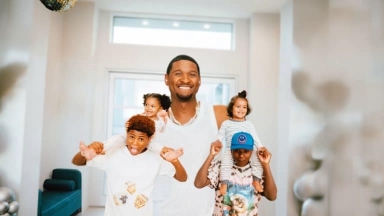 Usher smiling indoors surrounded by his four children posing together