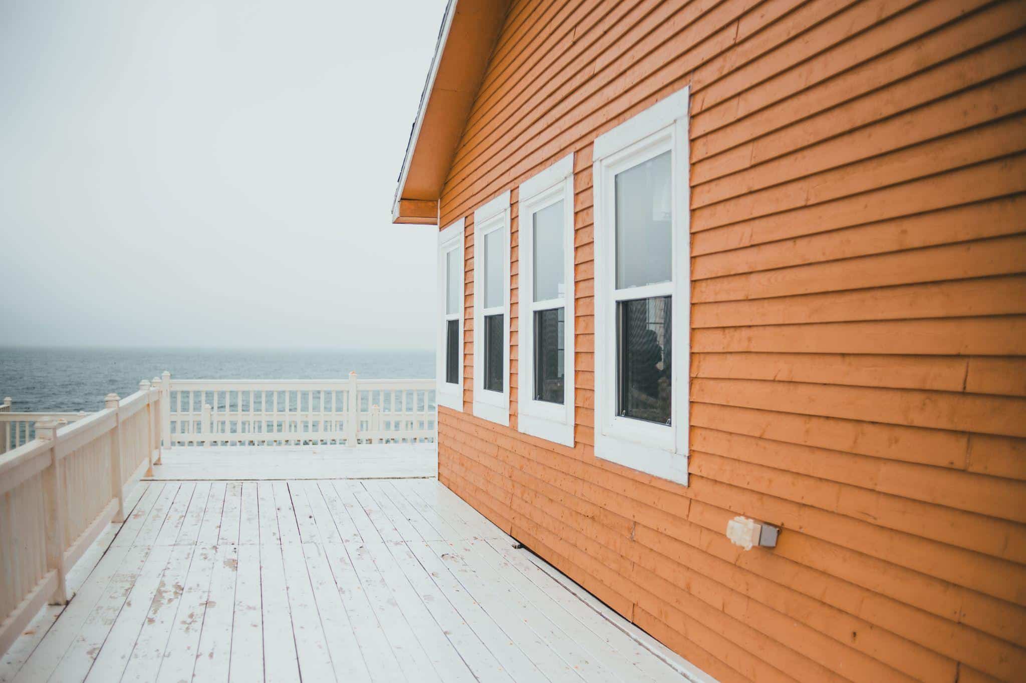 Orange wooden house with white window frames on a deck overlooking the ocean