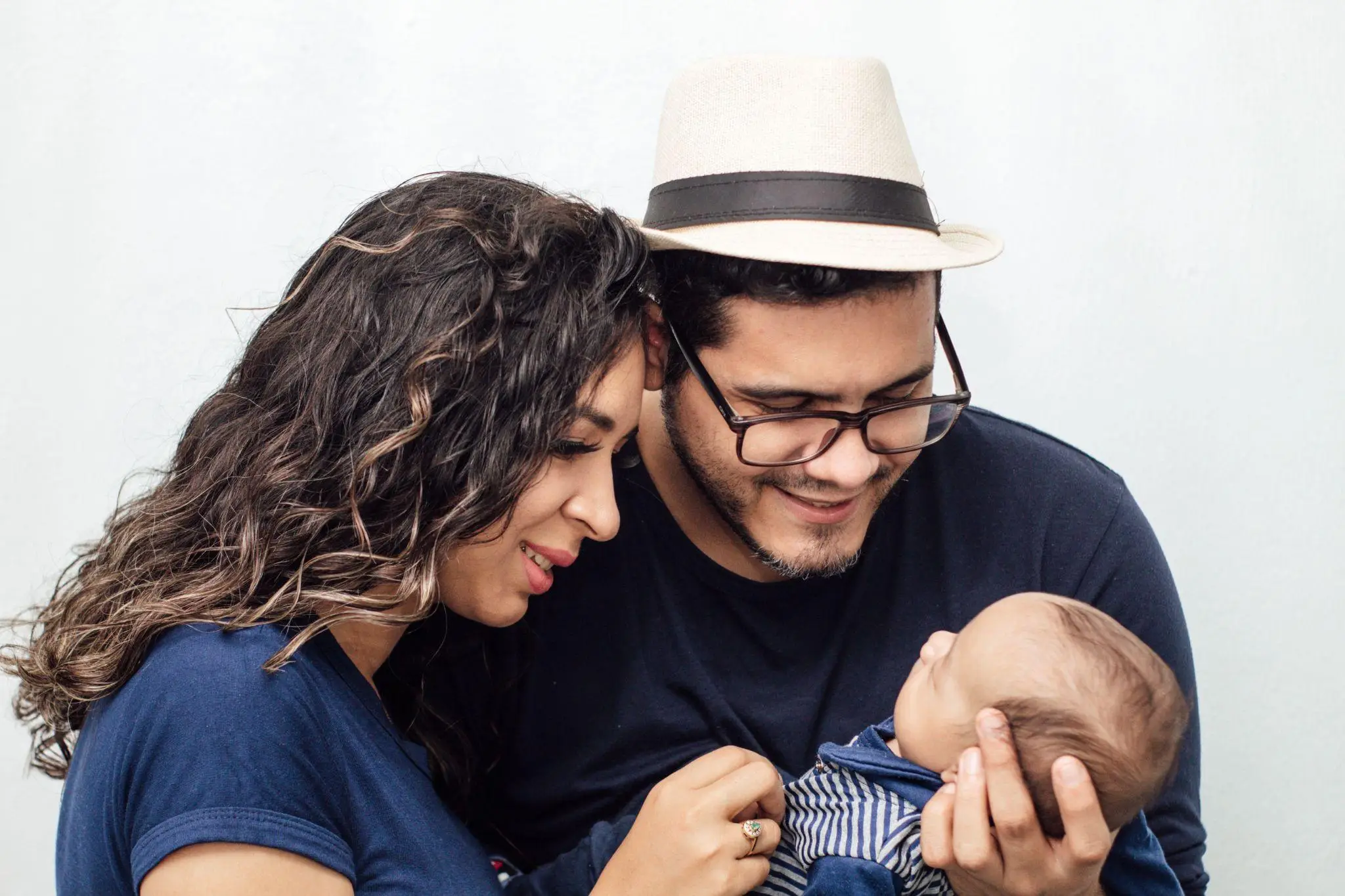 Parents smiling at their baby indoors wearing casual clothing