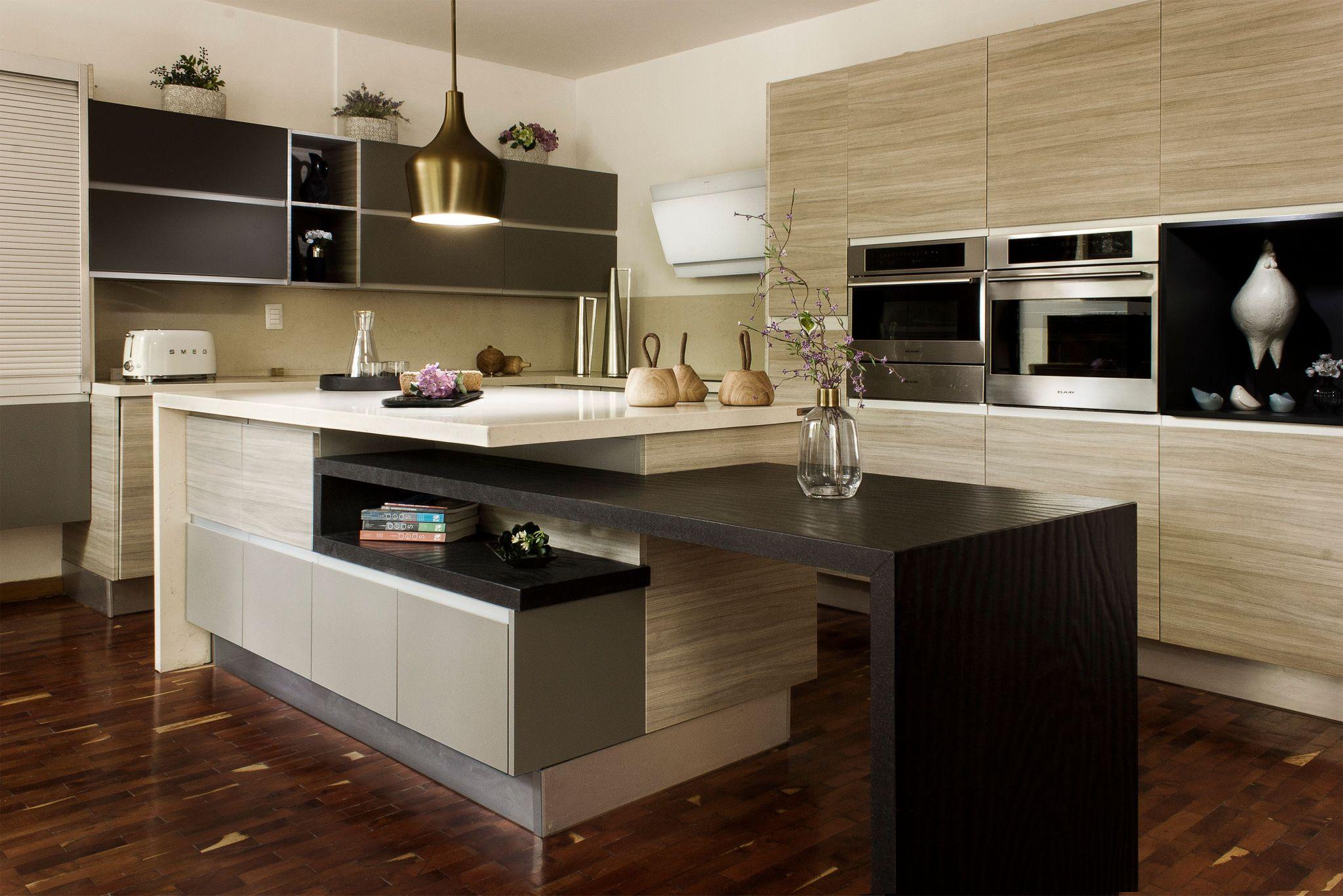 Modern kitchen with wooden cabinetry, pendant light, and decorative plants on polished countertops