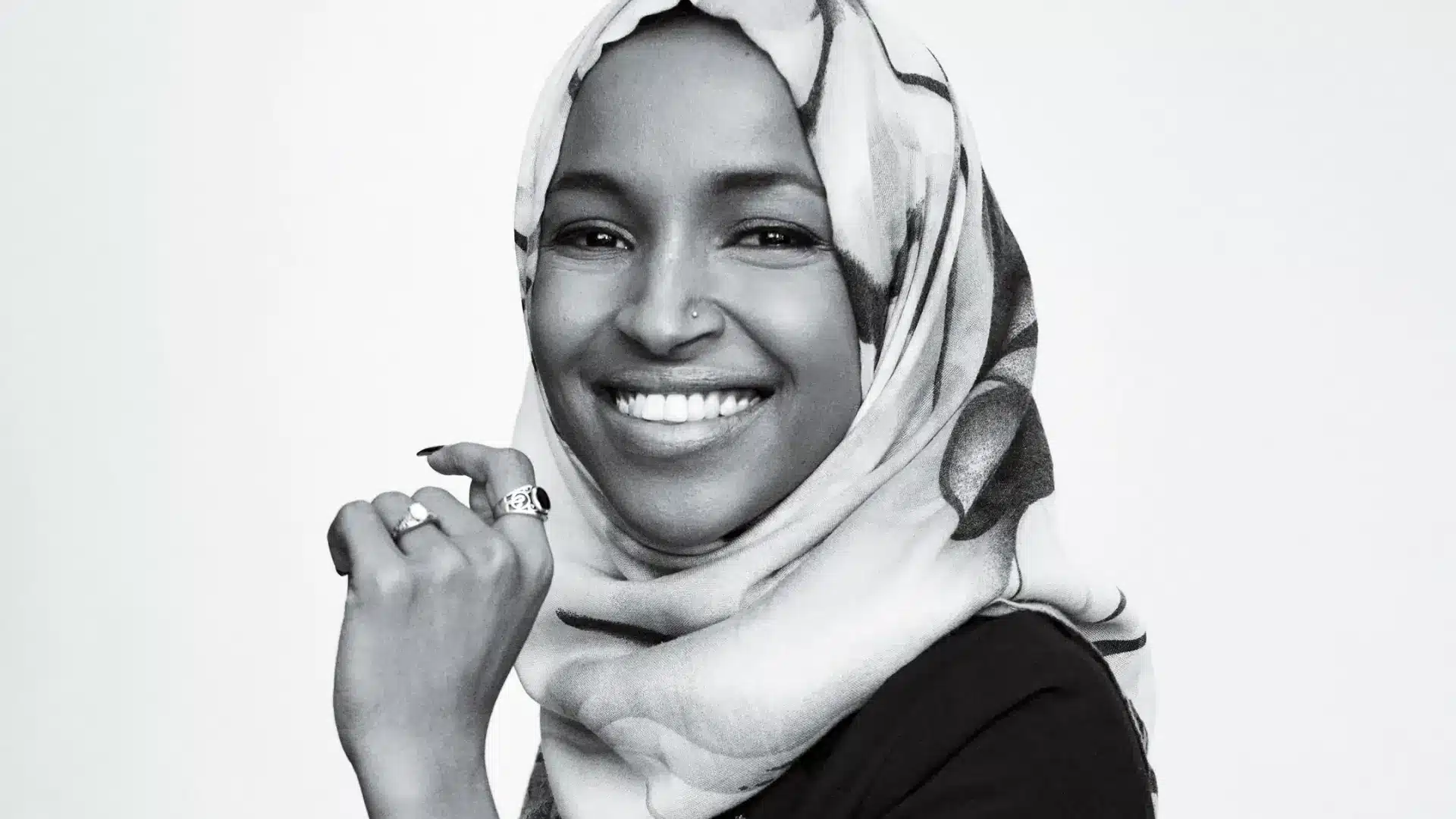 Black and white portrait of Congresswoman Ilhan Omar wearing a hijab and smiling