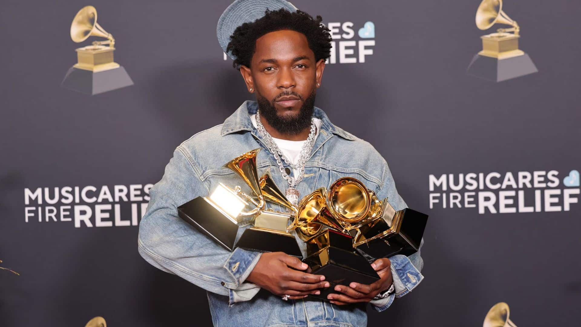 Kendrick Lamar holding Grammy awards highlighting his music career achievements.