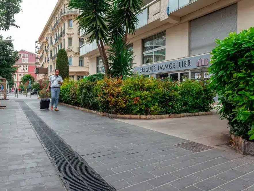Person walking with suitcase outside office building in urban street setting