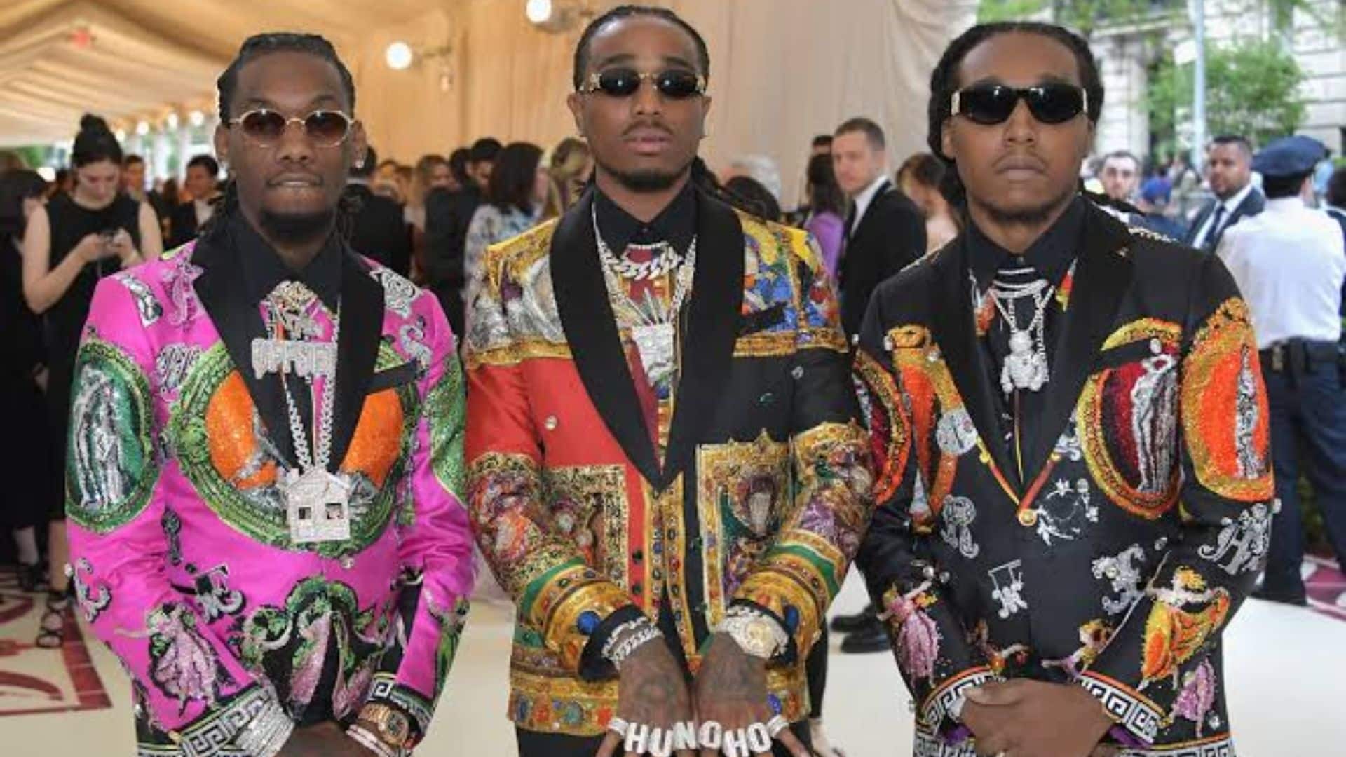 Offset, Quavo, and Takeoff posing together in colorful designer outfits.