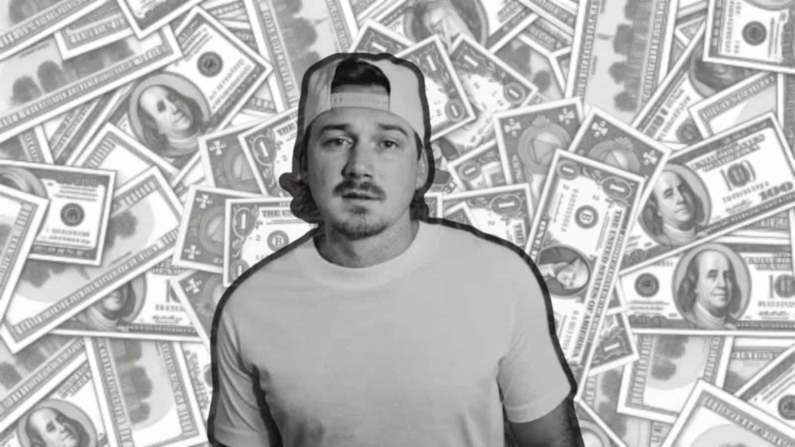 Black-and-white image of a Morgan Wallen in a cap standing in front of scattered dollar bills.