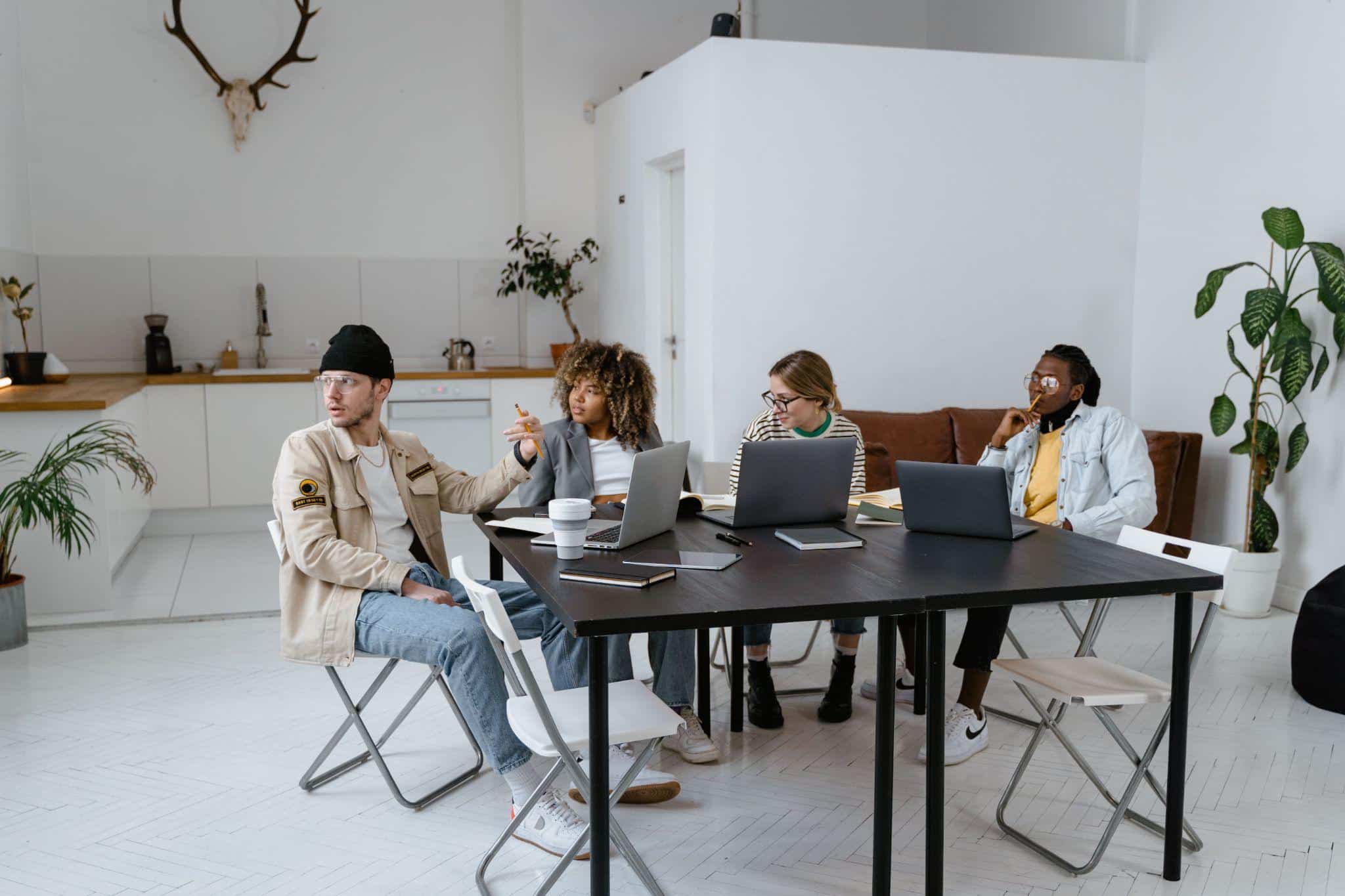 Group of people collaborating with laptops in a modern, minimalist office environment
