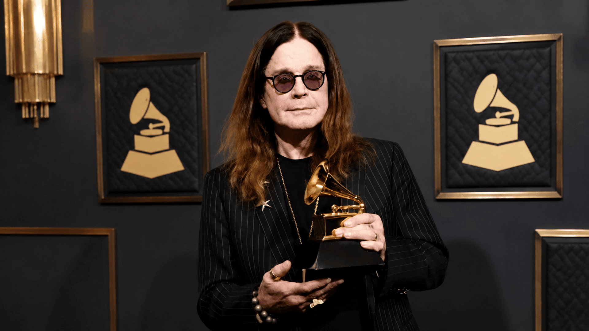 Ozzy Osbourne net worth feature image showing the singer with a Grammy award.
