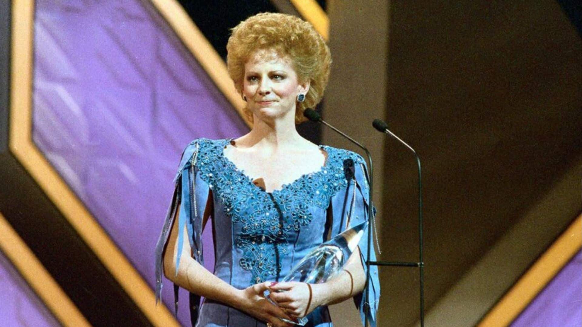 Reba McEntire accepting an honor on stage during a country music awards event