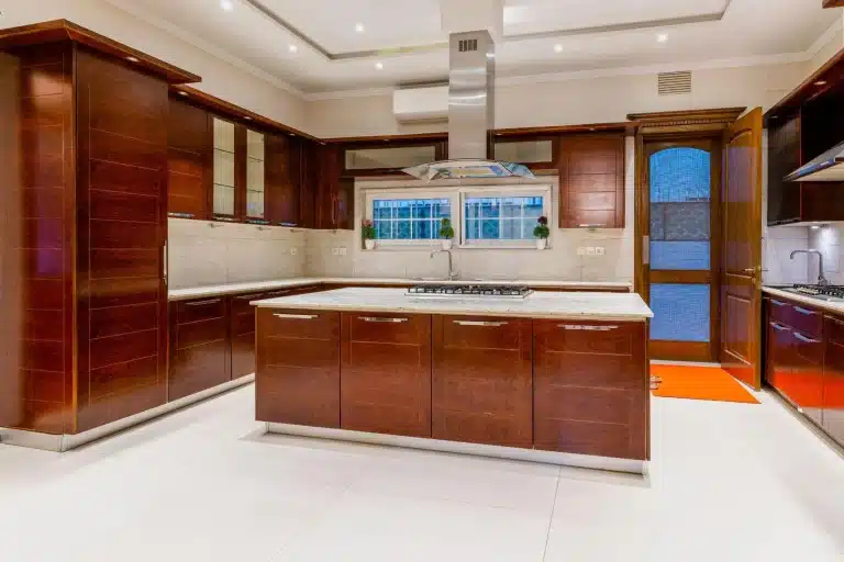 Spacious modern kitchen with dark wood cabinets and central island under bright lighting