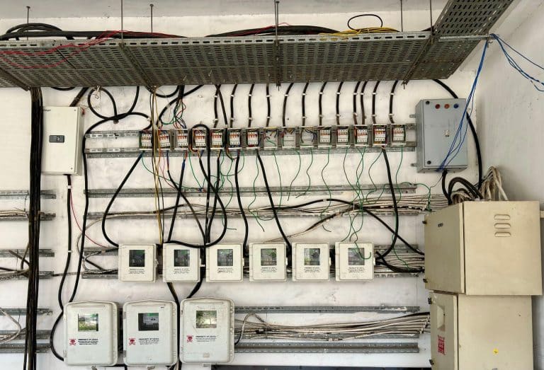 Electrical control panels with various wires and circuit breakers on a white wall indoors