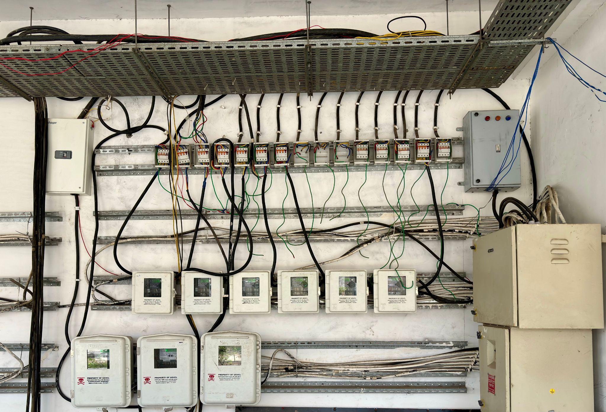 Electrical control panels with various wires and circuit breakers on a white wall indoors
