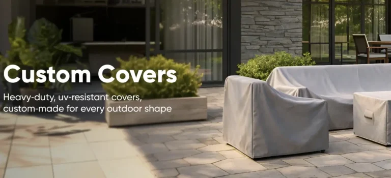 Outdoor patio furniture covered with gray protective covers, surrounded by leafy green plants